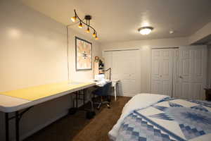 Bedroom featuring dark colored carpet, multiple closets, and built in study area