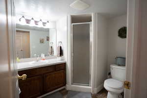Bathroom featuring vanity, a stall shower, wood finished floors, and a textured ceiling