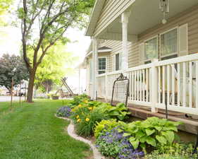 View of green lawn featuring covered porch
