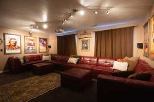 Carpeted cinema room with a textured ceiling and track lighting