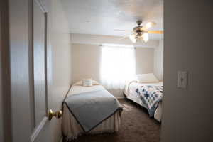 Bedroom with carpet flooring, a textured ceiling, and ceiling fan