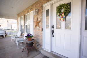 Entrance to property featuring a porch and brick siding