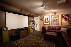 Home theater room featuring carpet and a textured ceiling
