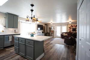 Kitchen featuring stainless steel dishwasher, gray cabinetry, a textured ceiling, light countertops, and decorative backsplash