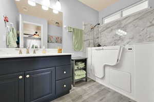 Bathroom featuring a shower, wood finished floors, plenty of natural light, and vanity