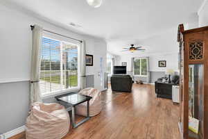 Living area featuring wood-type flooring, ceiling fan, and a textured ceiling