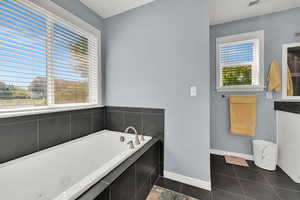 Bathroom with a tub with jets, tile patterned floors, and vanity