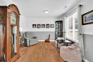 Living area with wood finished floors and crown molding
