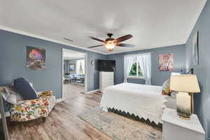 Bedroom featuring crown molding, wood finished floors, a ceiling fan, and a textured ceiling