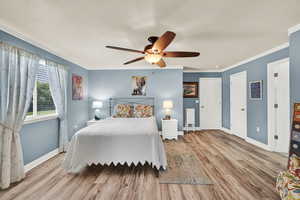 Bedroom featuring crown molding, wood finished floors, and a ceiling fan