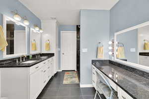 Bathroom with double vanity, tile patterned flooring, and a tile shower