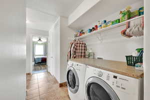 Laundry room featuring separate washer and dryer, a textured ceiling, a ceiling fan, and light tile patterned floors