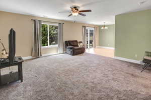 Sitting room featuring ceiling fan, carpet floors, and a chandelier