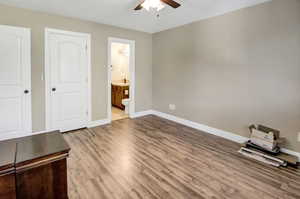 Primary bedroom featuring wood finished floors, ensuite bath, and ceiling fan