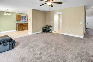 Living room with ceiling fan, recessed lighting, light colored carpet, light tile patterned flooring, and a chandelier