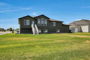 Rear view of house featuring a lawn and stucco siding