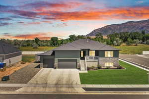 View of front of property featuring stone siding, a garage, driveway, and a mountain view