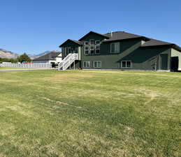 Back of house with stairs, a mountain view, and roof with shingles