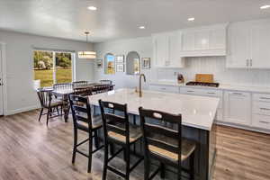 Kitchen featuring stainless steel gas stovetop, light countertops, decorative backsplash, a breakfast bar area, and recessed lighting