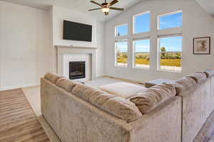 Living room featuring ceiling fan, a tile fireplace, light wood-type flooring, and lofted ceiling
