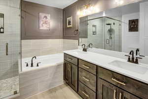 Bathroom with double vanity, a shower stall, and a bath
