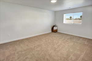 Carpeted spare room featuring baseboards