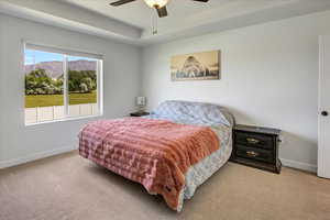 Bedroom featuring carpet, a tray ceiling, a mountain view, and a ceiling fan
