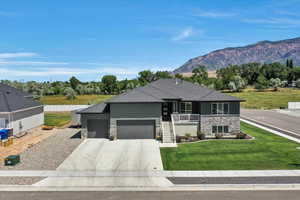 View of front of house featuring stone siding, a garage, concrete driveway, a mountain view, and stairs