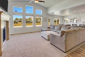 Living area with a ceiling fan, a glass covered fireplace, recessed lighting, and high vaulted ceiling