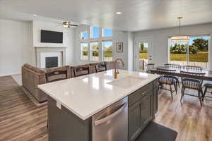Kitchen featuring dishwasher, ceiling fan, open floor plan, light wood-style floors, and light countertops