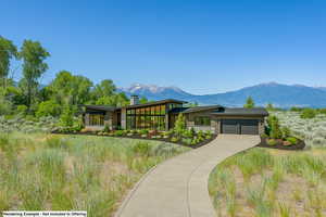 View of front of house with stone siding, a garage, driveway, and a mountain view