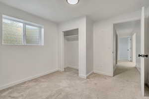 Unfurnished bedroom with light colored carpet and a closet