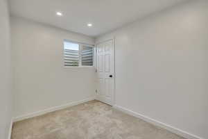 Empty room with light colored carpet and recessed lighting