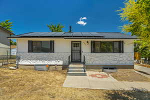 View of front facade featuring roof mounted solar panels, a metal roof, and a porch