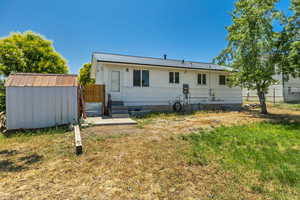 Rear view of property with a storage shed and a metal roof