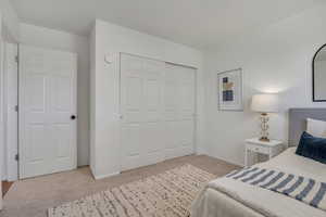 Bedroom with light colored carpet and a closet