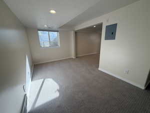 Carpeted spare room featuring a textured ceiling, electric panel, and recessed lighting