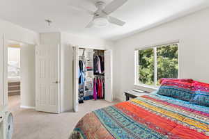 Bedroom featuring light colored carpet, a closet, and a ceiling fan