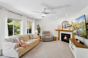 Living area with a glass covered fireplace, carpet, a ceiling fan, and recessed lighting