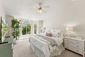 Carpeted bedroom featuring vaulted ceiling and a ceiling fan