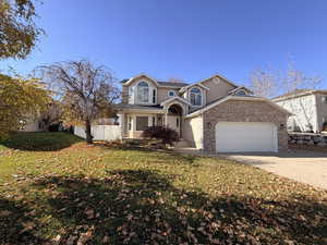 Traditional-style house featuring concrete driveway, an attached garage, brick siding, stucco siding, and a porch