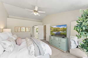 Bedroom featuring light carpet, vaulted ceiling, arched walkways, ceiling fan, and ensuite bath