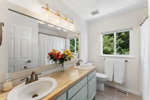 Full bath with double vanity, tile patterned floors, and curtained shower