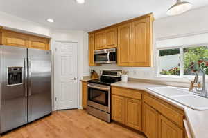 Kitchen featuring stainless steel appliances, light wood-type flooring, light countertops, recessed lighting, and brown cabinets