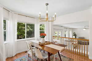 Dining area featuring light wood-style flooring, a chandelier, and a ceiling fan