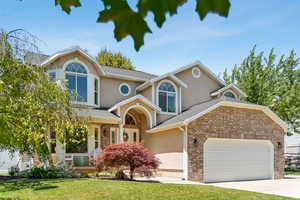 Traditional-style home featuring stucco siding, a garage, concrete driveway, a front yard, and a porch