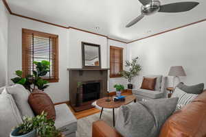 Living area featuring wood finished floors, a ceiling fan, ornamental molding, a fireplace, and recessed lighting