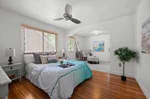 Bedroom 1, wood finished floors, ceiling fan, and ornamental molding