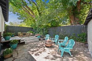 Fenced backyard with outdoor dining area, a fire pit, a patio, and a deck