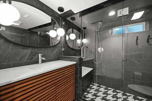 Bathroom featuring tile walls, vanity, and a shower stall